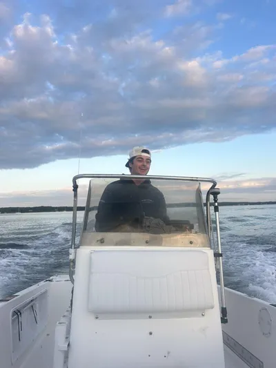 Brandon Bistrian smiling at the wheel of a center-console boat, running across the bay at dusk